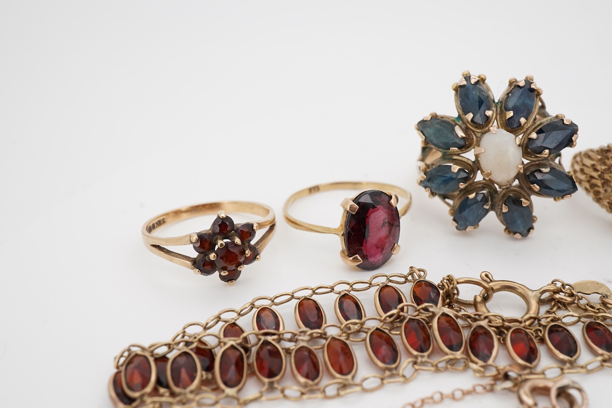 A group of jewels, comprising: two garnet cluster rings; a garnet bracelet; and a blue topaz ring, each mounted in 9ct gold, ring sizes H-M1/2, combined gross weight 13 grams; together with a marquise-shaped sapphire and
